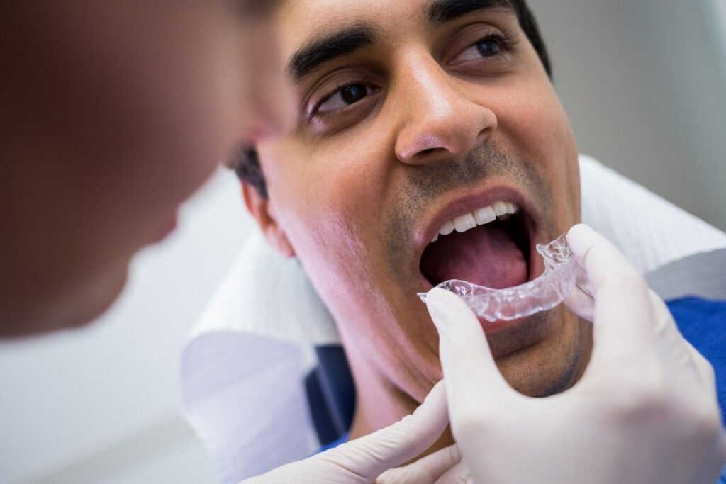 Invisible Aligners in Deira consultation showing a dentist demonstrating a clear aligner tray to a patient before orthodontic treatment